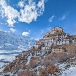 Spiti Winter Expedition Snow-clad Key Monastery against a backdrop of Himalayan peaks and blue sky with clouds in Spiti Valley