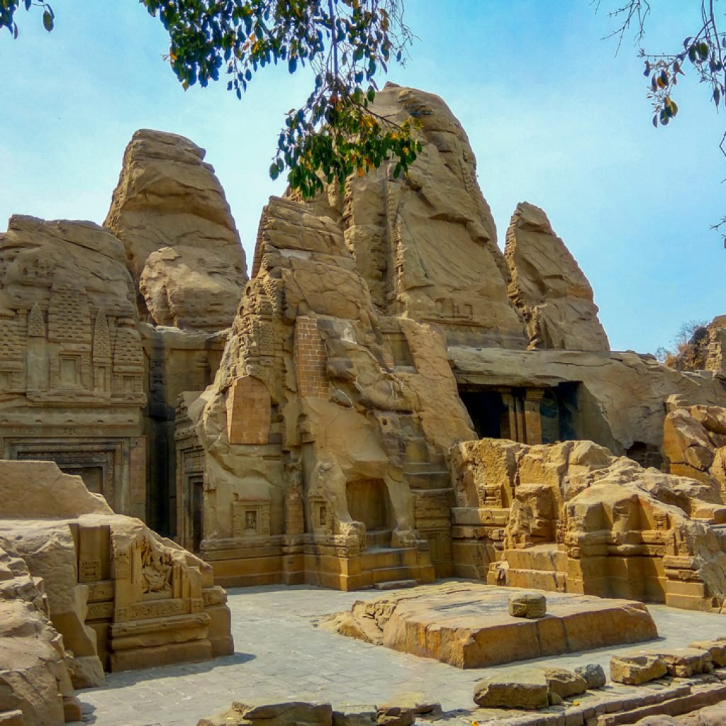 Ancient Masroor Rock Cut Temples with detailed carvings on sandstone under a clear blue sky.