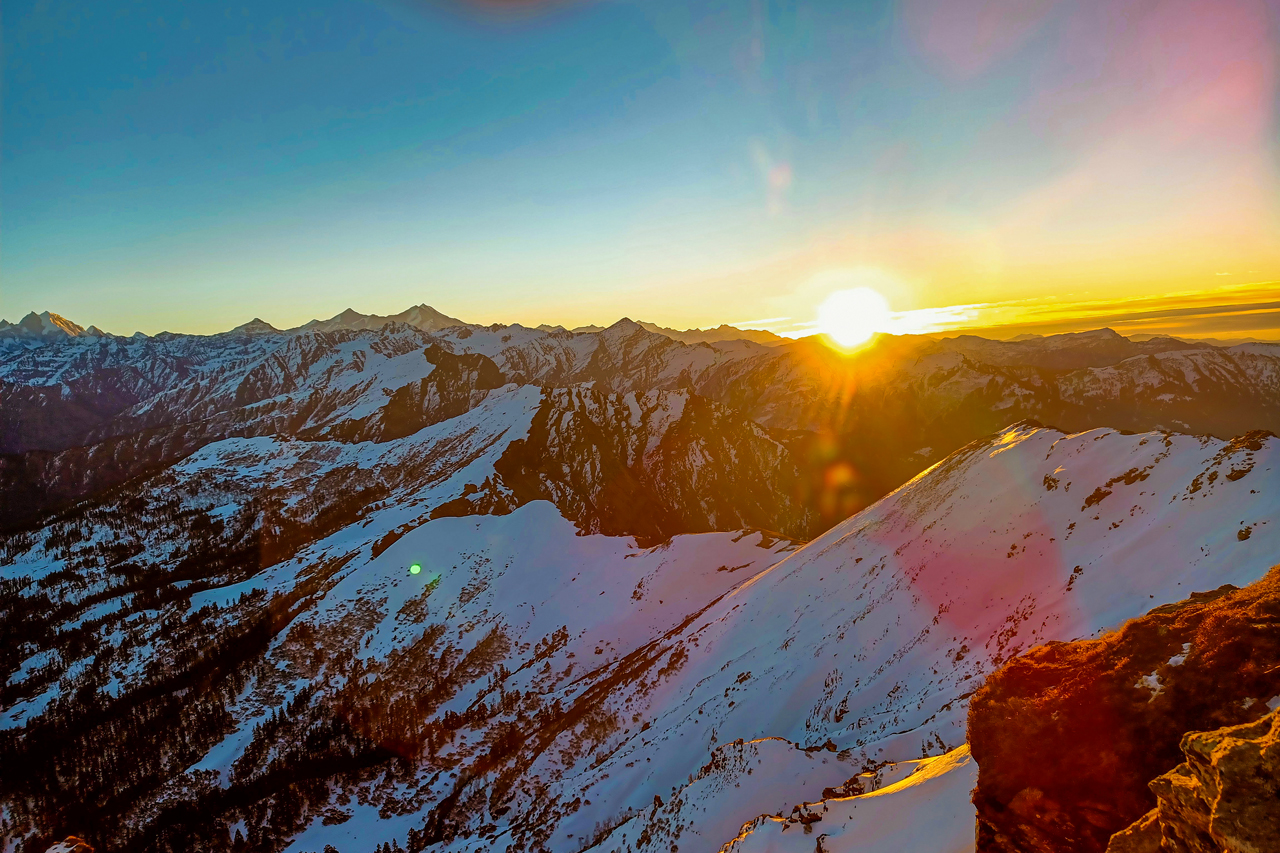 Sunrise over snow-covered mountains during winter at Kedarkantha.
